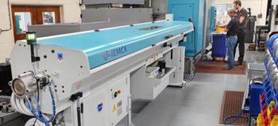 A machine in a warehouse with people working