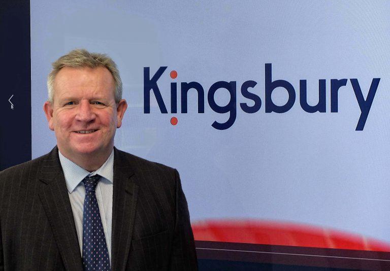 Richard Kingsbury standing in front of Kingsbury logo