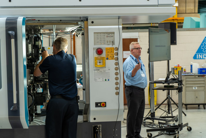Richard Kingsbury presenting to a crowd in front of a CNC machine