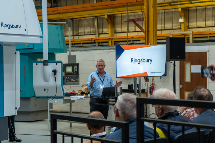 Richard Kingsbury presenting to a crowd in front of a CNC machine