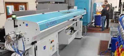 A machine in a warehouse with people working