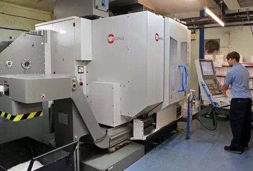Engineer working next to a Hermle machine in a warehouse